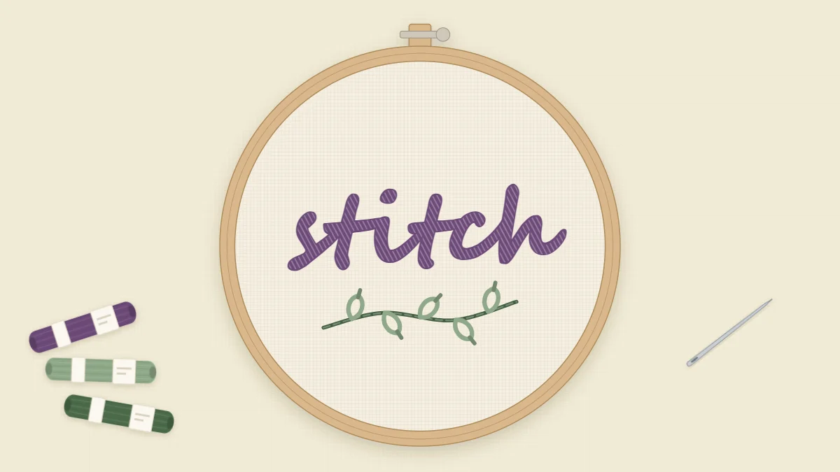 The word stitch embroidered in flowing script in a hoop on cream fabric, with a small leaf sprig underneath