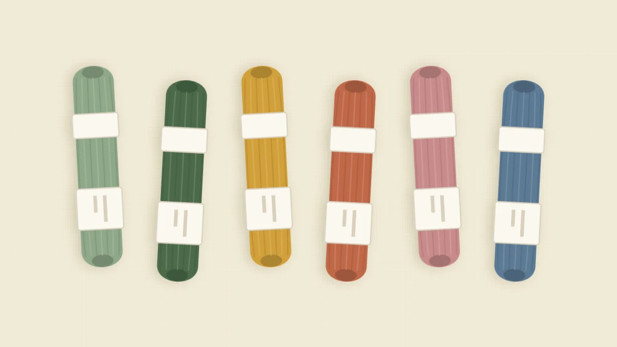 Six skeins of cotton embroidery floss in a row in sage green, deep green, mustard, terracotta, dusty rose and slate blue