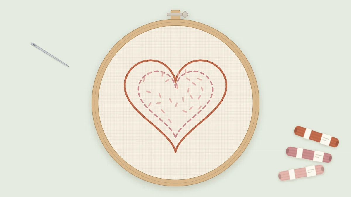 Finished heart embroidery in a 4-inch hoop with a terracotta outline, a dashed rose inner heart and scattered pink seed stitches