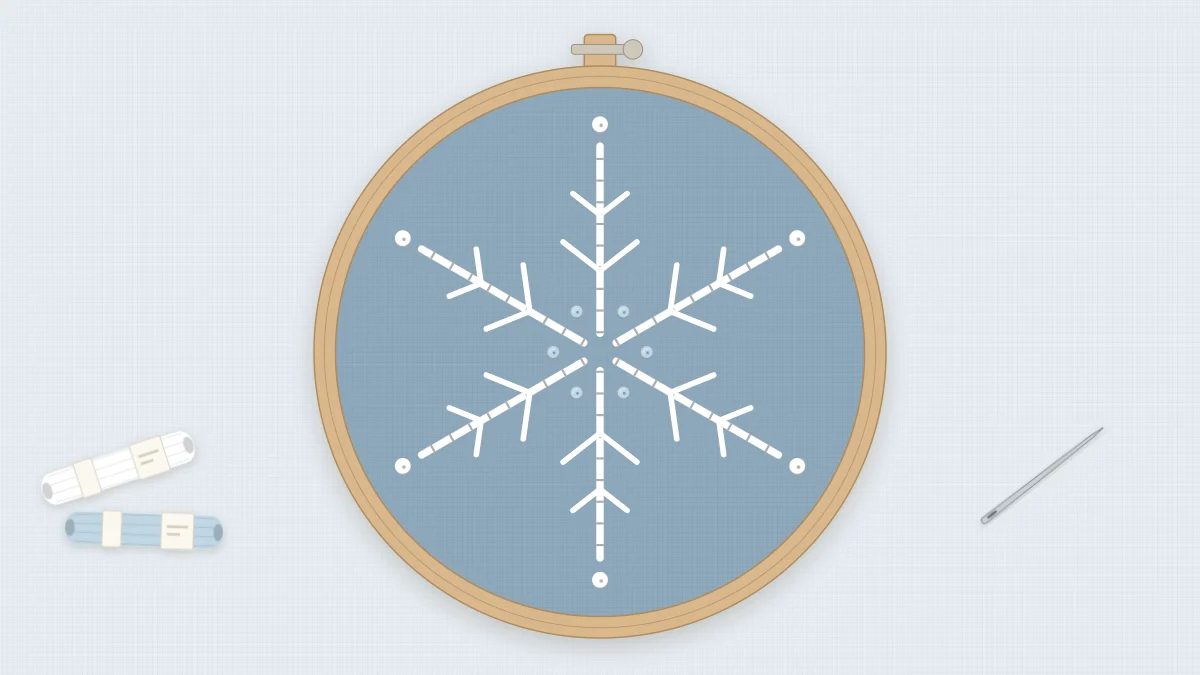 Finished white embroidered snowflake in a 4-inch hoop on dusty blue fabric